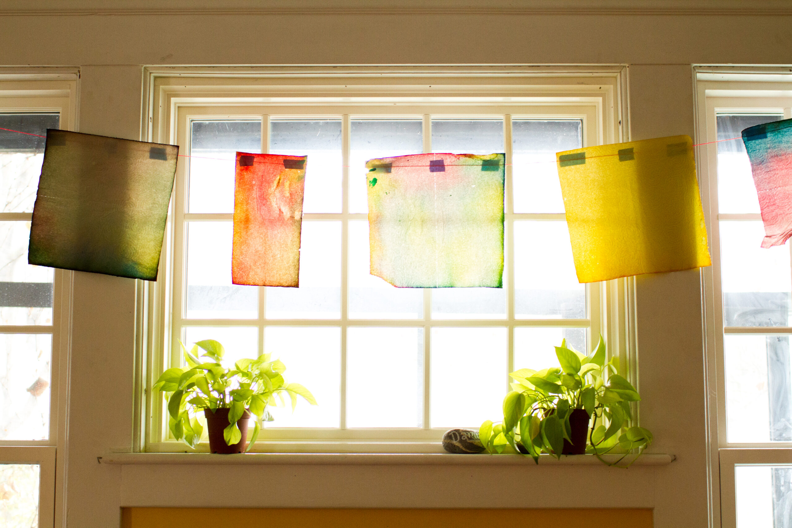 Photo of a window with transparent painted papers hanging in front of it